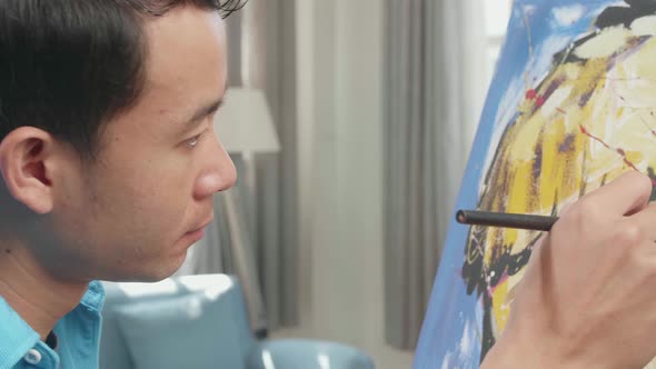 Close Up Side View Of An Asian Artist Man Holding Paintbrush And Thinking Before Painting