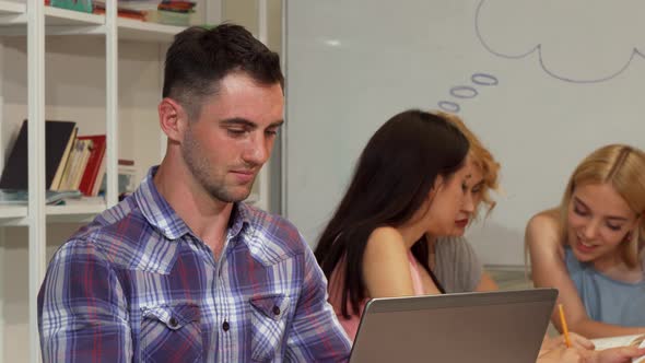 Cheerful Young Man Smiling Joyfully While Working on His Laptop