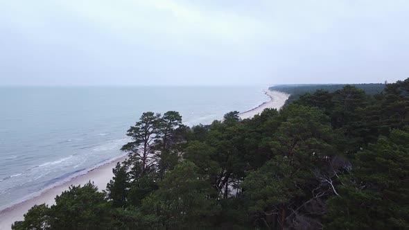 Aerial view of Baltic sea coastline at Bernati beach in Latvia, flying forward over tight coastal pi