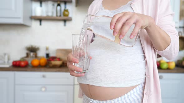 Closeup Of Pregnant Woman Pouring Water In Glass To Stay Hydrated.