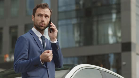 Businessman Talking on Phone by Car