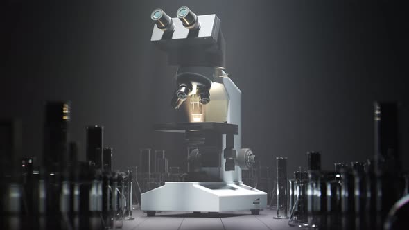 Modern microscope standing beside glassware under a spotlight in a laboratory.