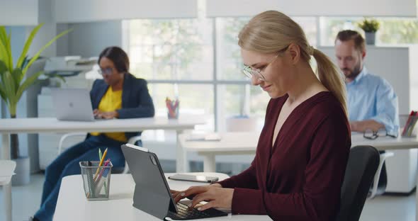 Side View of Female Manager Typing on Tablet Keyboard on White Table in Office Room