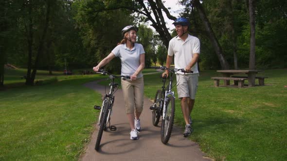 Mature couple walking with bicycles, slow motion