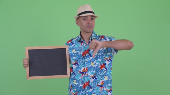 Stressed Multi Ethnic Tourist Man Holding Blackboard and Giving Thumbs Down