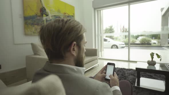 Businessman text messaging with smartphone in lobby