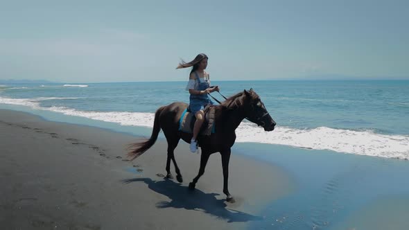 Cute Chinese Teenager Rides a Horse On The Beach In Bali