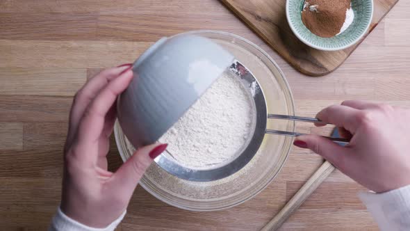 Girl Sifting Flour On Fine Mesh Strainer Falling Into Baking Bowl For Carrot Cake. - high angle