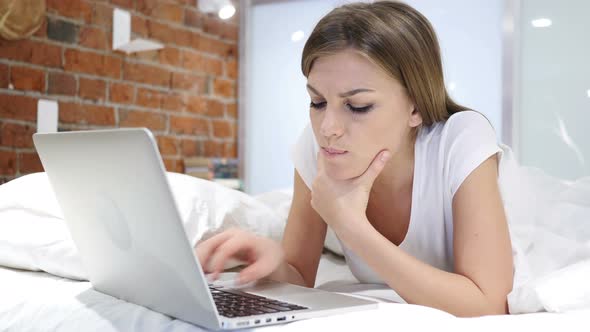 Thinking Pensive Woman in Bed Working on Laptop at Night