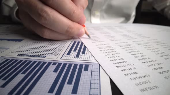 Accountant analyzing business marketing data on paper dashboard at office table.