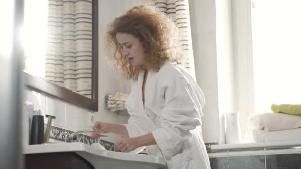 Concentrated Caucasian Redhead Woman Washing Hands in Bathroom