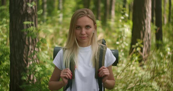 Portrait of a Young Woman Traveler in the Sun Looking Directly Into the Camera and Smiling Flirting