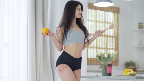 Medium Shot Portrait of Charming Seductive Middle Eastern Woman Holding Orange and Anticellulite