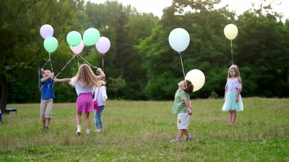 Group of Happy Children Playfully Running with Multicolored Balloons