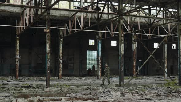 Soldier with Machine Gun Looking Around in Destroyed Factory