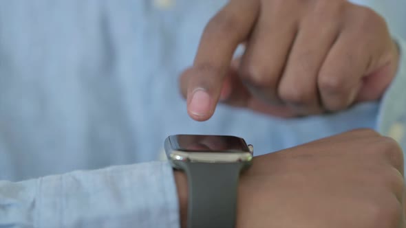 Close Up of Serious Young African Man Using Smartwatch