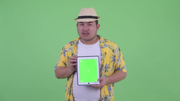 Stressed Young Overweight Asian Tourist Man Showing Digital Tablet