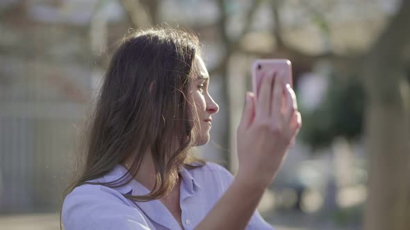 Woman Having Video Chat on Phone in Park, Showing Surroundings