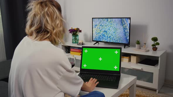 Woman sitting on sofa Using Laptop with Greenscreen and Chroma Key.