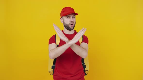 Serious Delivery Man in Red Uniform with Backpack Expressing Negativity Crossing Hands and Shaking