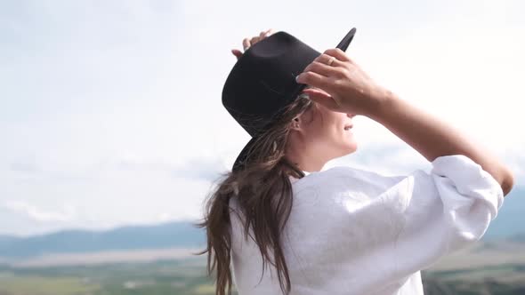 Attractive Brunette in a Hat and White Shirt Is Enjoying Nature in the Mountains. Portrait of a