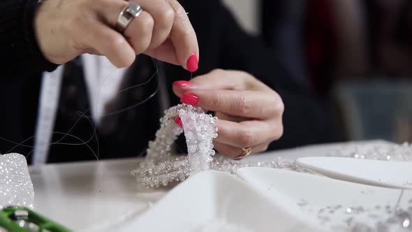 Closeup of Female Hands with Pink Manicure Holding Needle and Thread and Decorating Exclusive