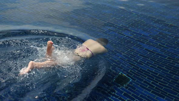 Professional Swimmer in Bikini Dives in Transparent Water