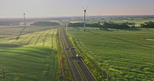 Wind turbines near highway at sunrise, aerial view