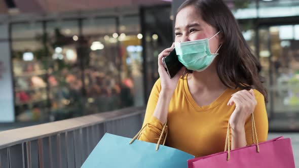 Asian woman wearing face mask. Happy woman with shopping bags