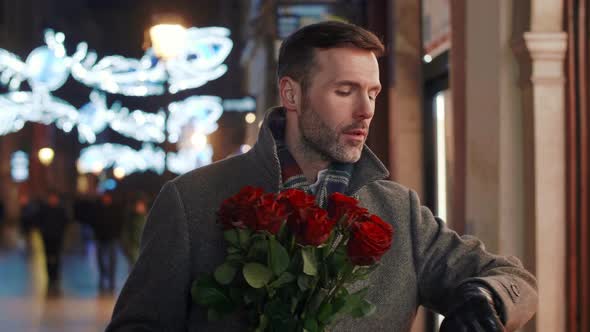 Worried man with bunch of roses waiting for his lady