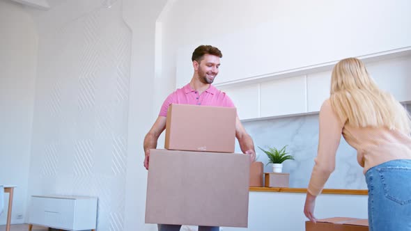 Long haired blonde in pullover puts brown cardboard box in bearded man hands