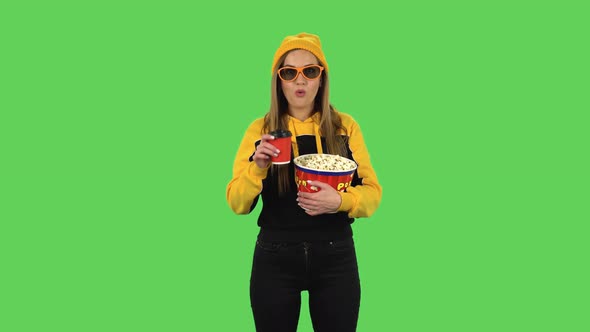 Modern Girl in Yellow Hat in 3D Glasses Is Watching a Movie, Eating Popcorn and Drinking Tasteless