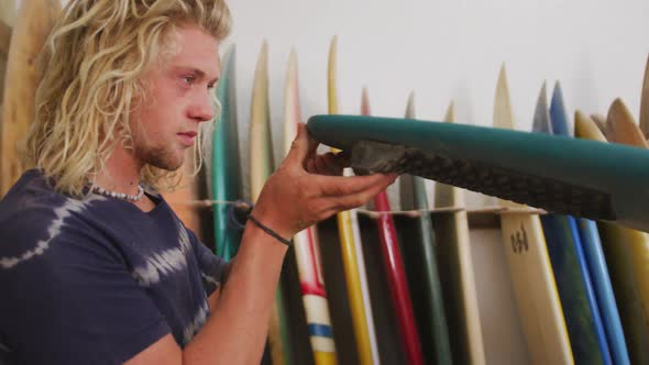 Caucasian male surfboard maker checking one of the surfboards in his studio