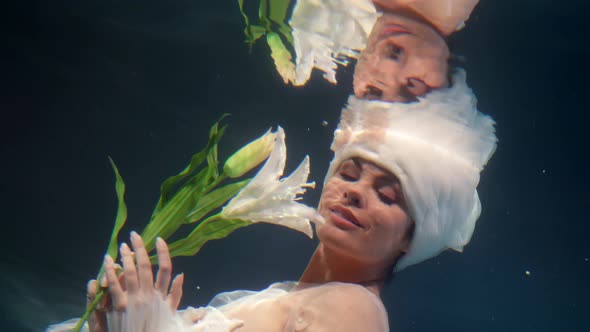 Romantic and Fabulous Female Portrait Underwater Beautiful Woman is Holding White Lily in Hands