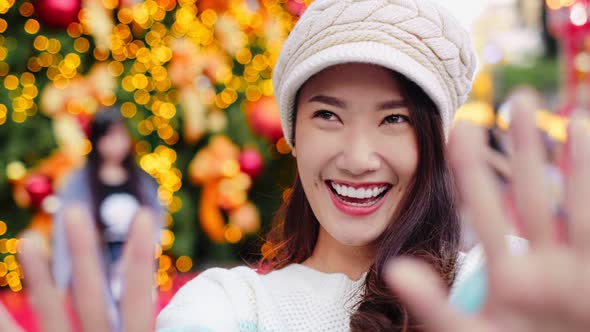 Happy young asian woman taking a selfie photo near christmas tree