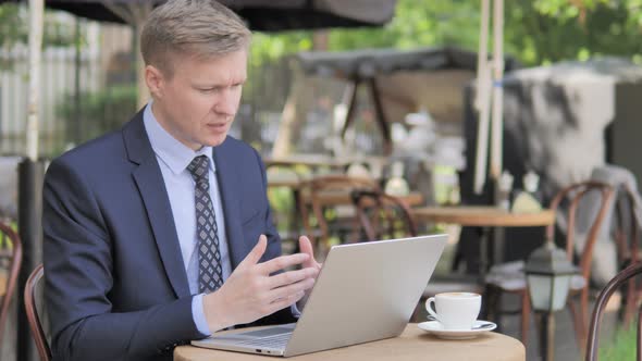 Online Video Chat by Businessman Sitting in Outdoor Cafe