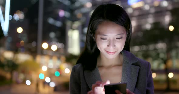 Business woman use of mobile phone in city at night