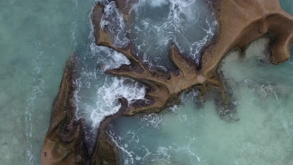 Aerial view from above of waves crashing on rocks La Digue Seychelles