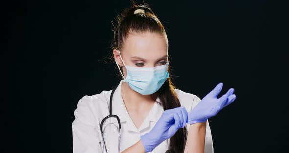 A Serious Female Medical Professional with a Face Mask White Lab Coat and Stethoscope Puts on