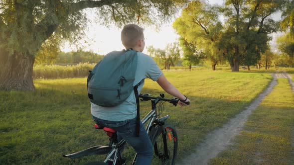 Teenage Boy Rides Bike in City Park at Sunny Day. Healthy Lifestyle Concept