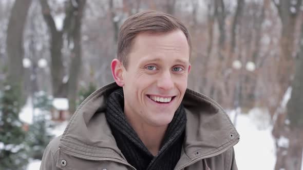 Portrait of a Happy Young Man Showing Gesture OK Standing in the Forest in Winter