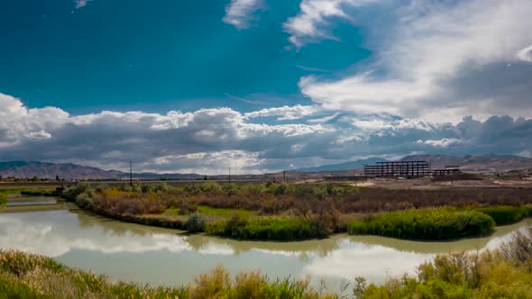 Cloudscape over a river with the sky reflection on the water and a highway and construction project