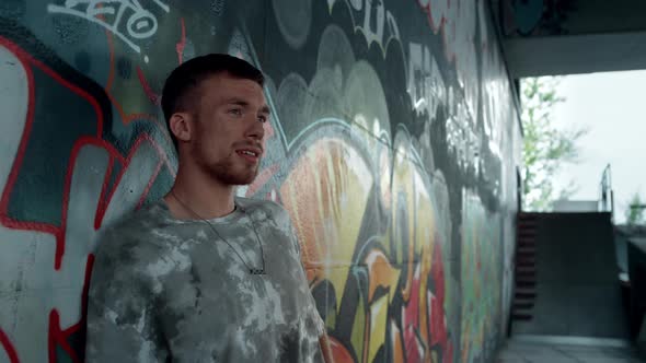 Young Hipster Relaxing Near Wall with Graffiti