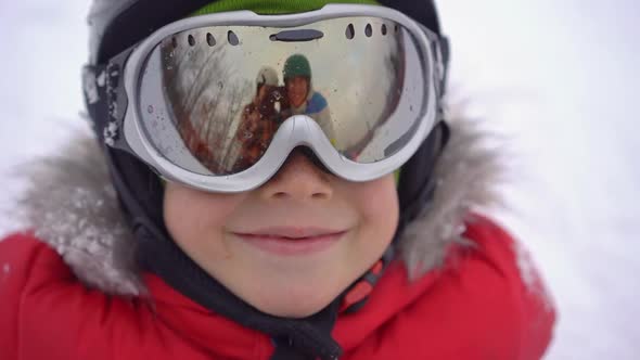 Mom and Dad Are Reflected in the Boy Ski Goggles. Mom and Dad Teach a Boy To Ski or Snowboard