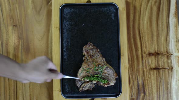 Steak being placed and cooked on hot stone barbecue, overhead view