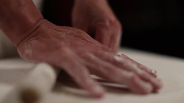 Hand rolling dough to make stuffed Chinese gyoza dumplings - isolated on hands and rolling pin