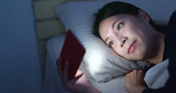 Woman use of mobile phone and lying on bed