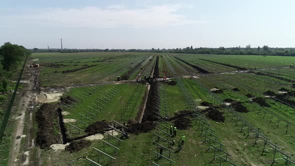 High Angle View of a Green Field with Rows of Solar Panel Racks Construction