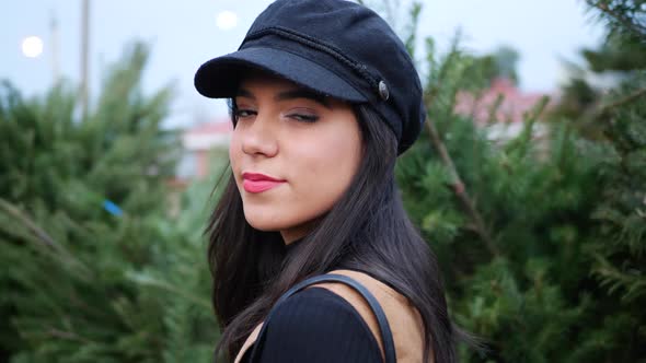 A hispanic woman smiling in the holiday spirit shopping for a festive christmas tree.