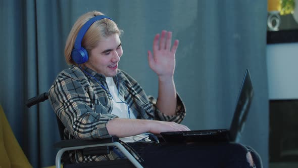 Blonde Man in a Wheelchair Talking with Somebody on Video Call Using His Laptop